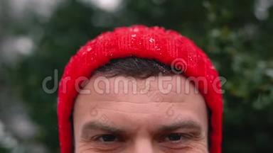 一个戴红帽子的男人在户外下雪时的肖像